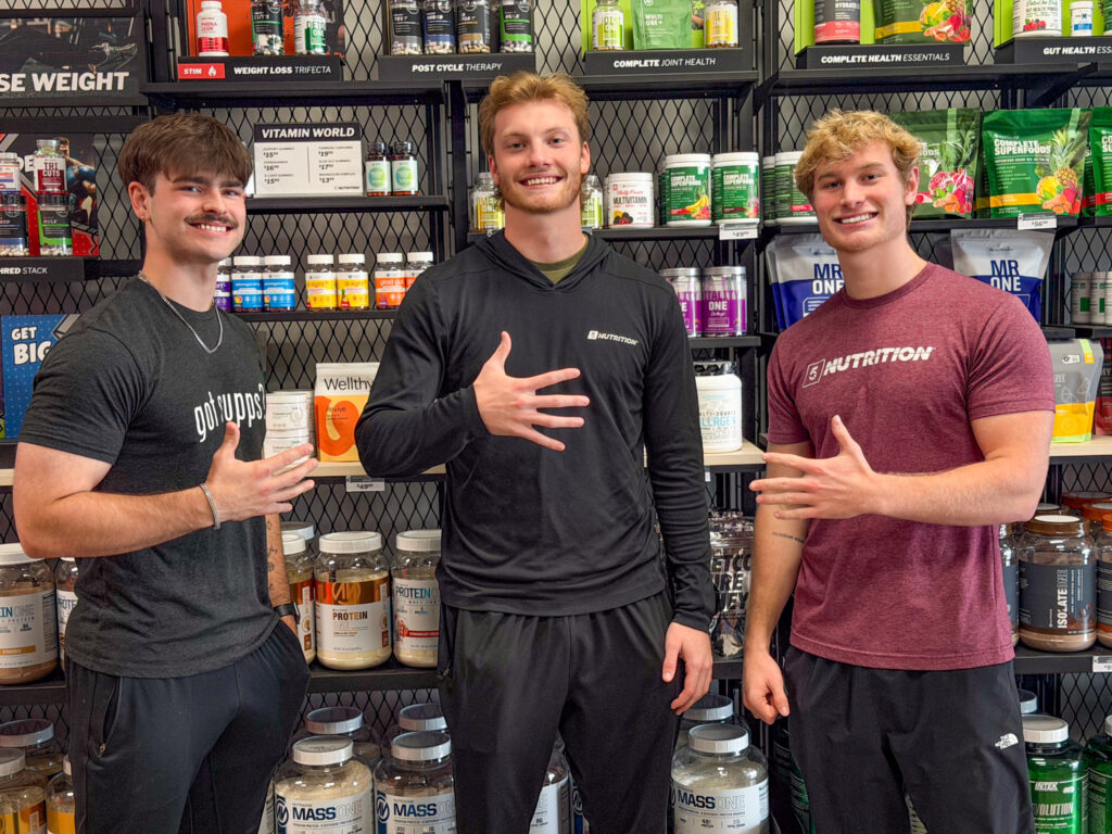 3 men posing in front of a wall of supplements at 5 star pocatello